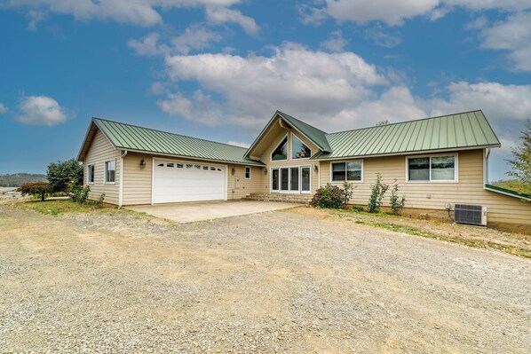 A two-story house with a green metal roof, beige siding, and a front garage. - Vineyard Farmhouse in Oakland w/ Hot Tub! (Oakland)