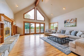 Relax in a spacious living area with a high vaulted ceiling, stone fireplace, and comfortable seating.