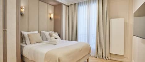 A hotel room with a large bed, a built-in headboard, a radiator, and a large window with curtains.