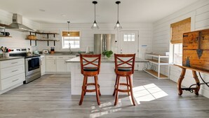 A spacious kitchen with white cabinetry, a stainless steel range, and two wooden bar stools. - 1 Block to Beach: Home w/ Patio in Murrells Inlet! (Murrells Inlet)