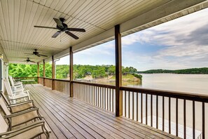 Eine überdachte Terrasse mit Holzbänken, Geländer und Blick auf einen Fluss und Grünflächen.