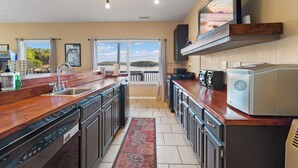 A modern kitchen with a large island, built-in appliances, and a view of a lake. - Lakefront Ozarks Home: Tiki Bar, Pool, Deck, Views (Camdenton)