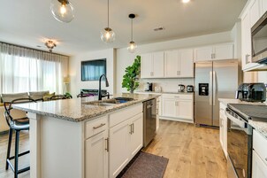 Uma cozinha moderna com ilha central, eletrodomésticos de aço inoxidável e iluminação pendente.
