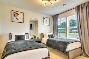 A hotel room with two beds, a large mirror, and a window with curtains.
