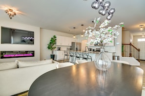 A modern kitchen with white cabinets, a dining area with a round table, and a staircase leading to another level.