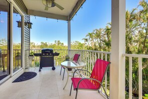 A covered outdoor patio with a glass table and chairs, a grill, and a view of palm trees. - Dock, Kayaks & On-site Pond: Terra Ceia Home (Palmetto)