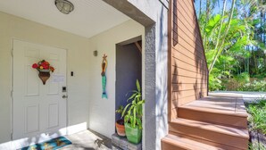 A wooden staircase leading to a door with a doormat, a potted plant, and a wall-mounted decoration. - Dock, Kayaks & On-site Pond: Terra Ceia Home (Palmetto)