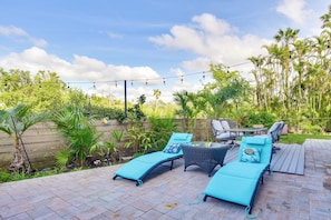 A patio with lounge chairs and a table, surrounded by greenery and palm trees. - Dock, Kayaks & On-site Pond: Terra Ceia Home (Palmetto)