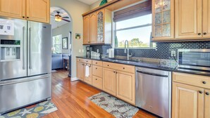A modern kitchen with wooden cabinets, stainless steel appliances, and a large window. - Dock, Kayaks & On-site Pond: Terra Ceia Home (Palmetto)