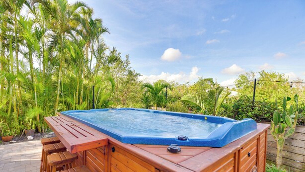 A wooden hot tub with a blue interior, surrounded by lush greenery and a wooden deck. - Dock, Kayaks & On-site Pond: Terra Ceia Home (Palmetto)