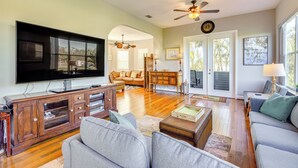 A spacious living room with a large flat-screen TV, wooden entertainment center, and comfortable seating. - Dock, Kayaks & On-site Pond: Terra Ceia Home (Palmetto)