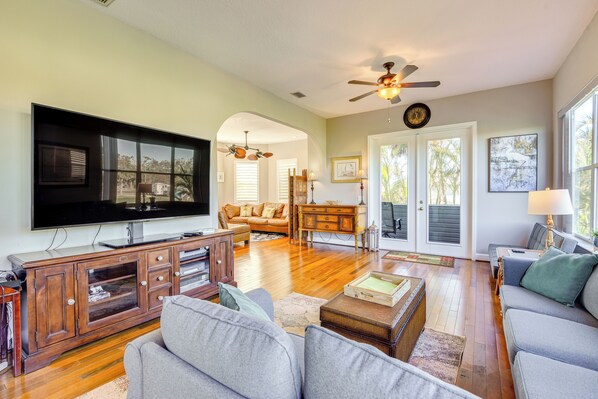 A spacious living room with a large flat-screen TV, wooden entertainment center, and comfortable seating. - Dock, Kayaks & On-site Pond: Terra Ceia Home (Palmetto)