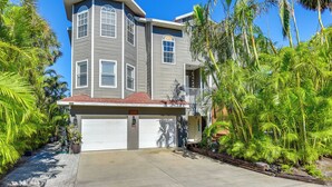A two-story house with a garage, surrounded by lush greenery and palm trees. - Dock, Kayaks & On-site Pond: Terra Ceia Home (Palmetto)