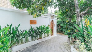 A paved pathway leading to a building with a white exterior and a wooden door. - 2BR Villa Seminyak with Pool (Seminyak, Badung Regency)