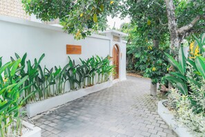 A paved pathway leading to a building with a white exterior and a wooden door. - 2BR Villa Seminyak with Pool (Seminyak, Badung Regency)