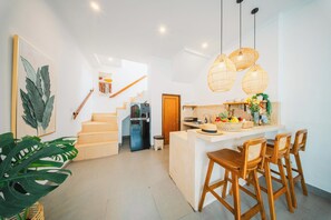 A modern kitchen with wooden bar stools, a staircase, and a dining area. - 2BR Villa Seminyak with Pool (Seminyak, Badung Regency)