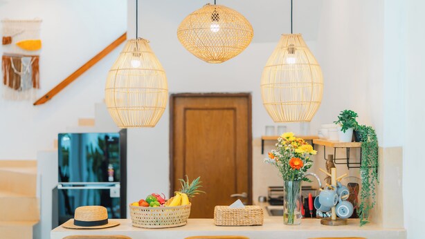 A kitchen with wicker pendant lights, a fruit basket, a vase with flowers, and a wooden door. - 2BR Villa Seminyak with Pool (Seminyak, Badung Regency)