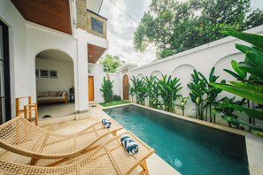 A pool area with lounge chairs and a small garden. - 2BR Villa Seminyak with Pool (Seminyak, Badung Regency)
