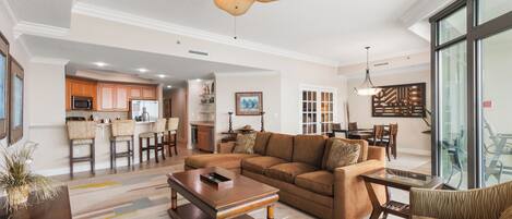 A spacious living room with a large brown sectional sofa, a wooden coffee table, and a ceiling fan.