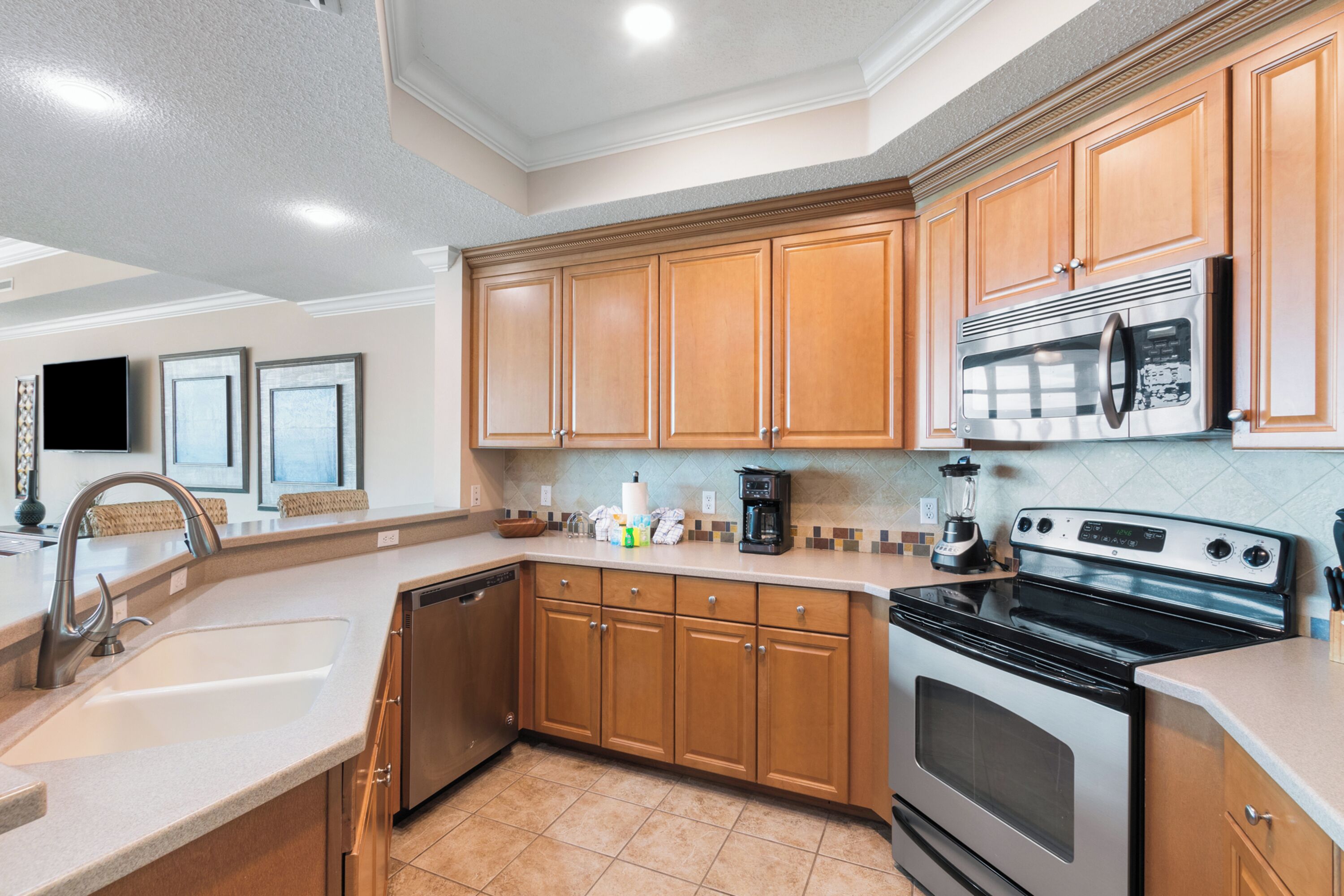 A modern kitchen with wooden cabinets, stainless steel appliances, and a tiled backsplash.
