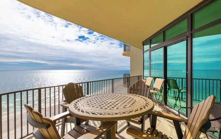 A balcony with a round table and chairs, overlooking a body of water.