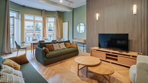 Un salon moderne comprenant un canapé, un téléviseur et un coin repas avec une table et des chaises.