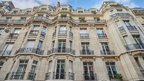 Ein mehrstöckiges Gebäude mit aufwendigen architektonischen Details, darunter Balkone mit schmiedeeisernen Geländern und dekorative Steinornamente.