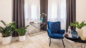 Una sala de estar moderna con un sillón azul, una mesa de centro de vidrio y dos plantas en macetas.