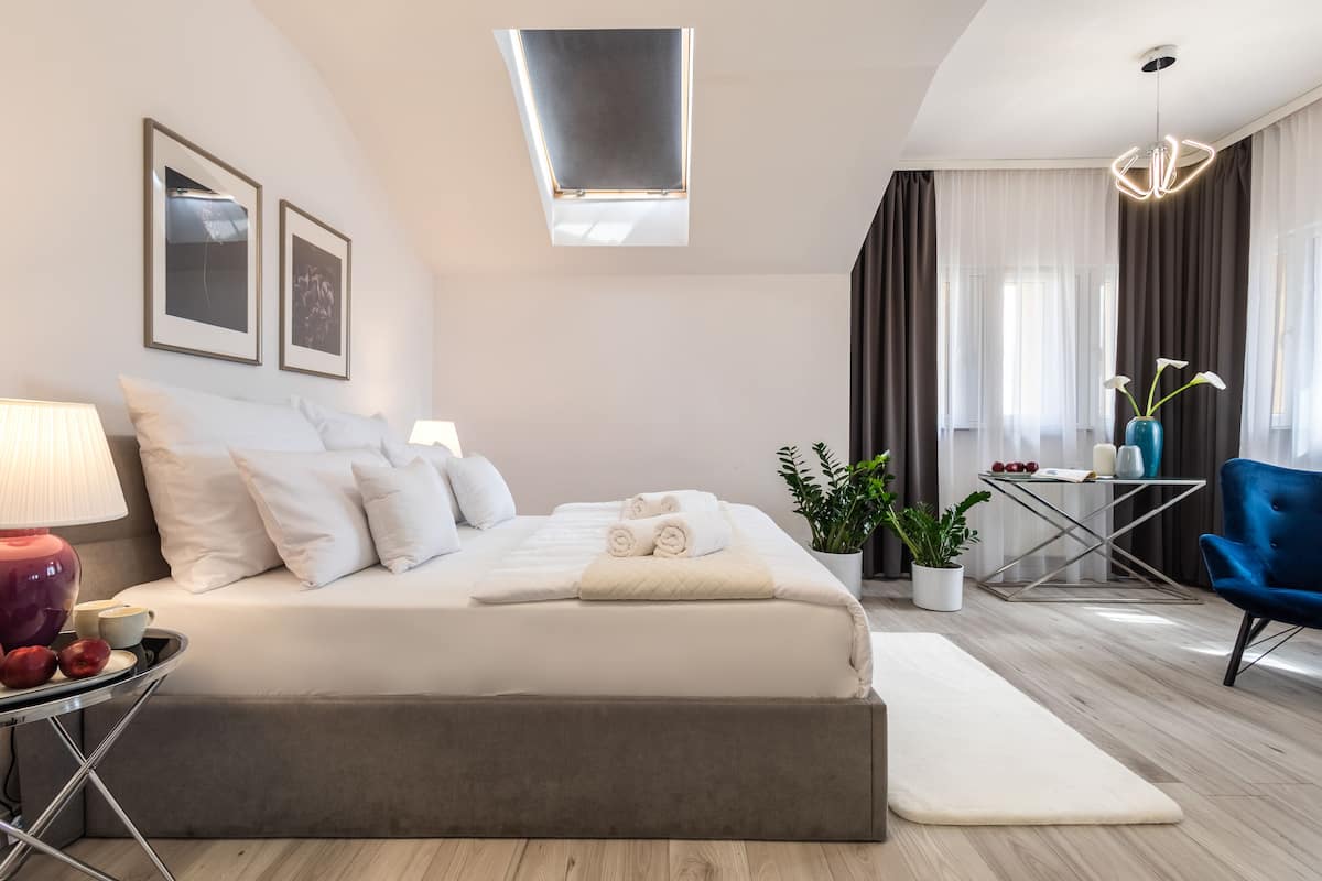 A modern bedroom with a large bed, bedside tables, a desk, and a chair.