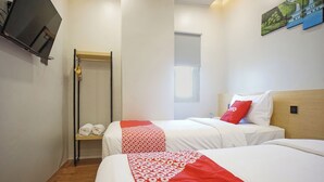 A hotel room with two beds, a TV mounted on the wall, a window, and a painting. - OYO 92956 Travelbiz Hotel (Medan)