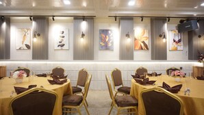 A conference room with round tables, gold chairs, and artwork on the walls. - OYO 92956 Travelbiz Hotel (Medan)