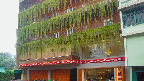 A multi-story building with a flat facade, featuring horizontal lines of greenery. - OYO 92956 Travelbiz Hotel (Medan)