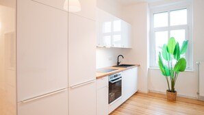 A modern kitchen with white cabinets, a wooden countertop, and a built-in oven.