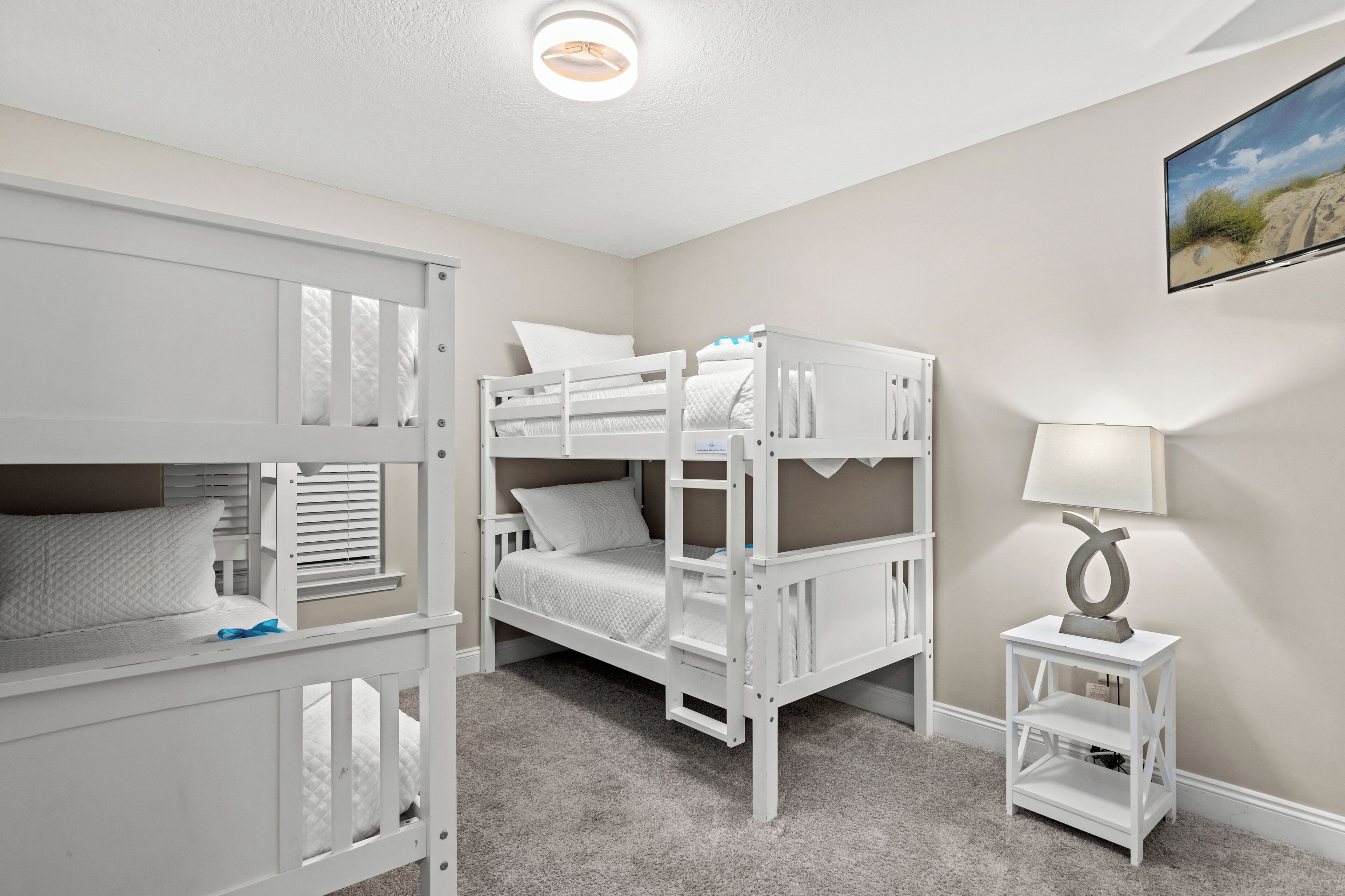 Ein Schlafzimmer mit Etagenbett, einem kleinen weißen Nachttisch und einer Lampe.