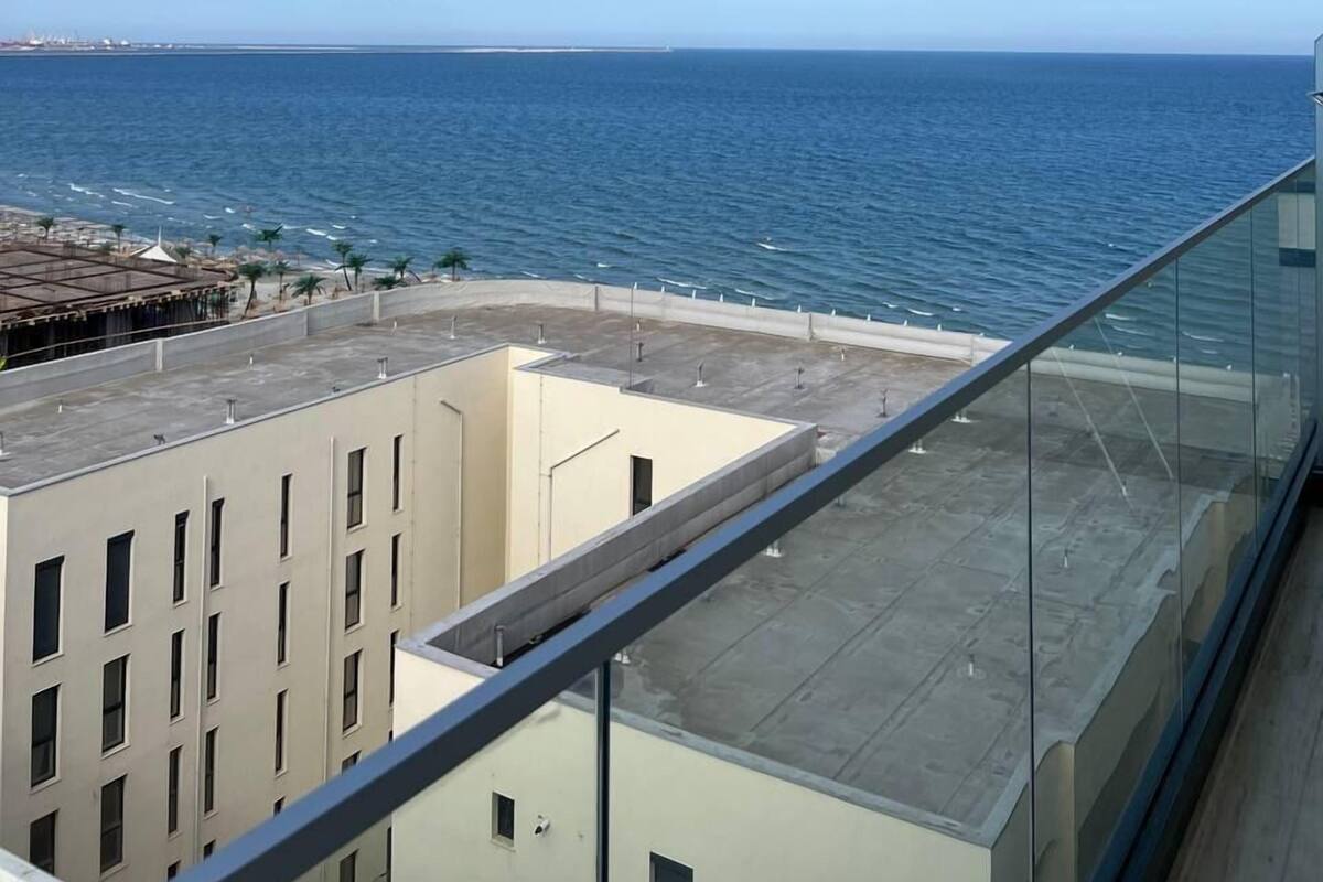 A balcony with a clear view of the ocean and a distant shoreline.