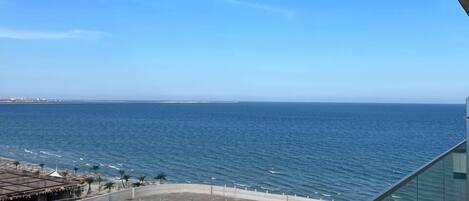 A balcony with a clear view of the ocean and a distant shoreline.