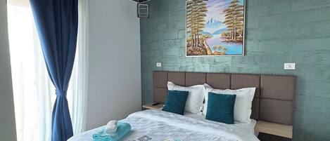 Una habitación de hotel moderna con una cama grande, un cuadro en la pared y una lámpara de techo original.