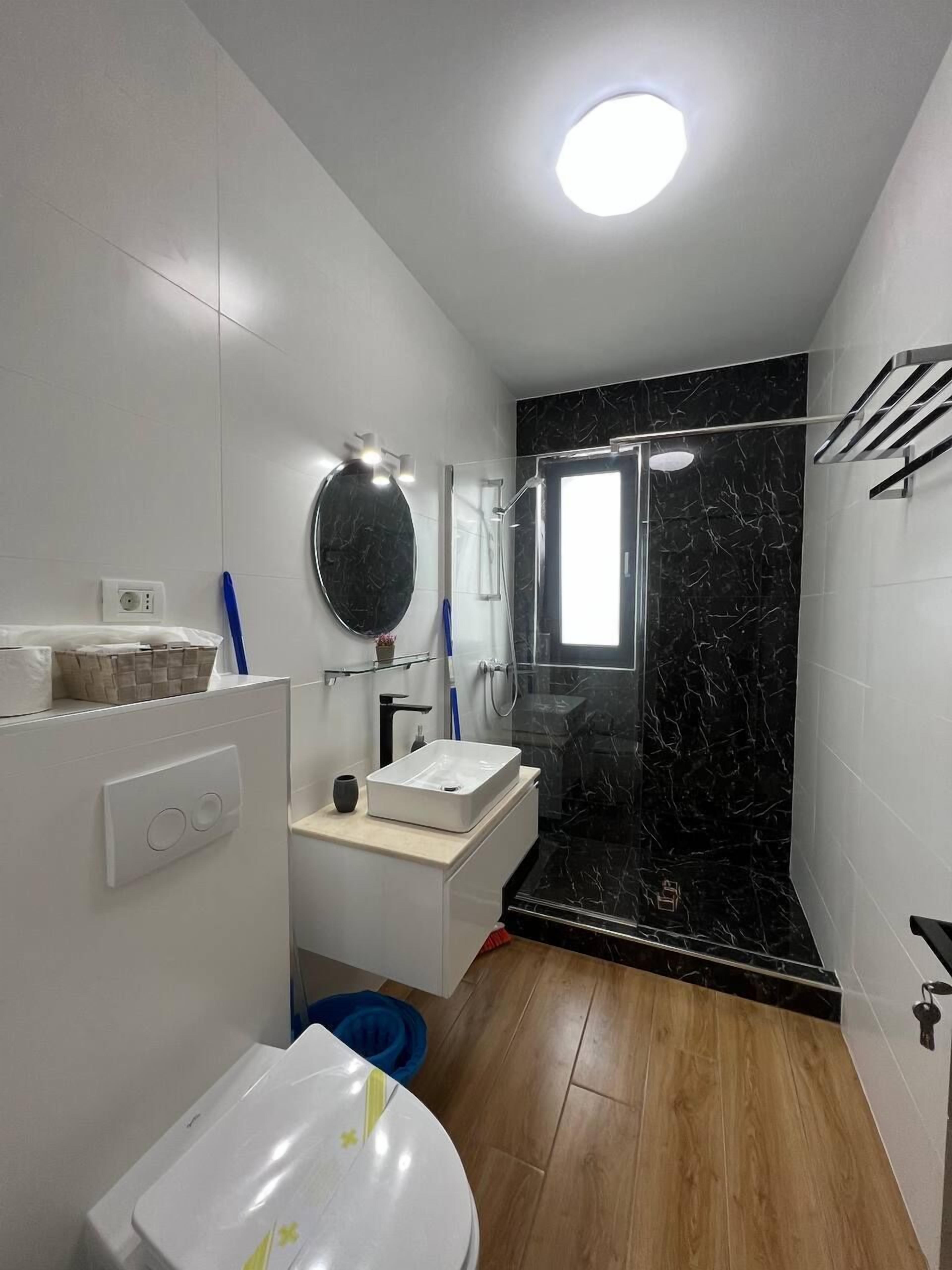 Une salle de bain moderne avec un meuble-lavabo blanc, une cabine de douche noire et des toilettes.