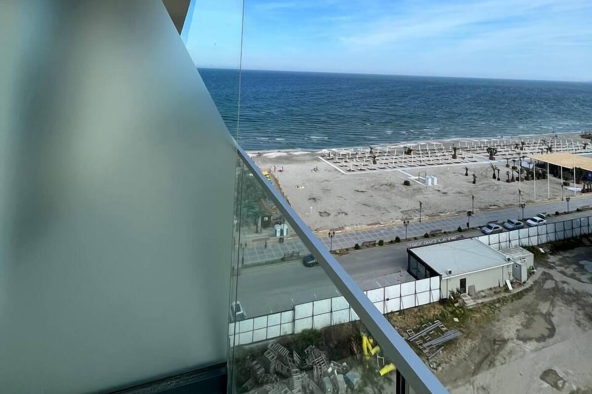 A view from a balcony overlooking a beach with a clear sky.
