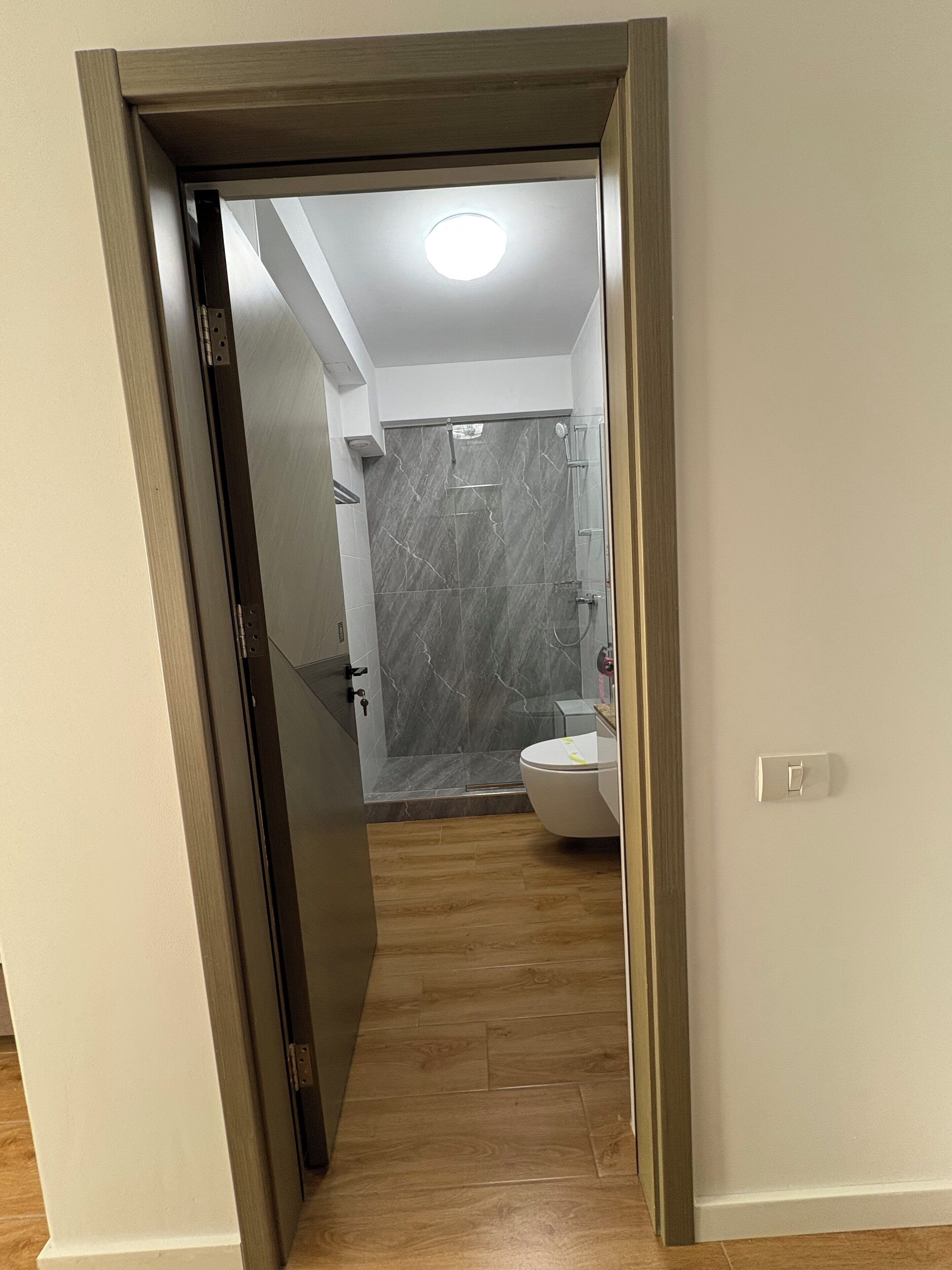 Een badkamer met een douche, toilet en marmeren wanden.