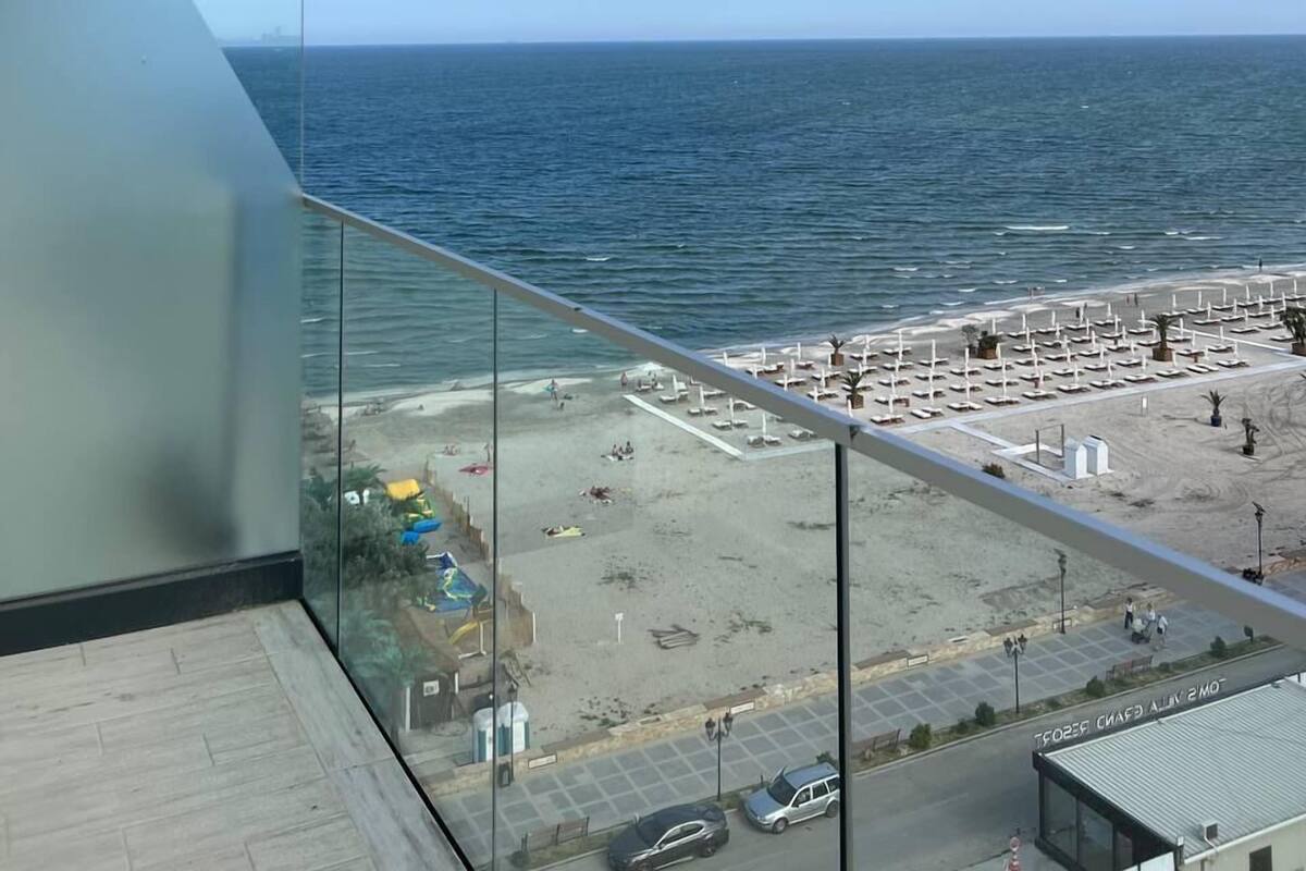 A balcony with a clear view of the sea and a beach with sun loungers.