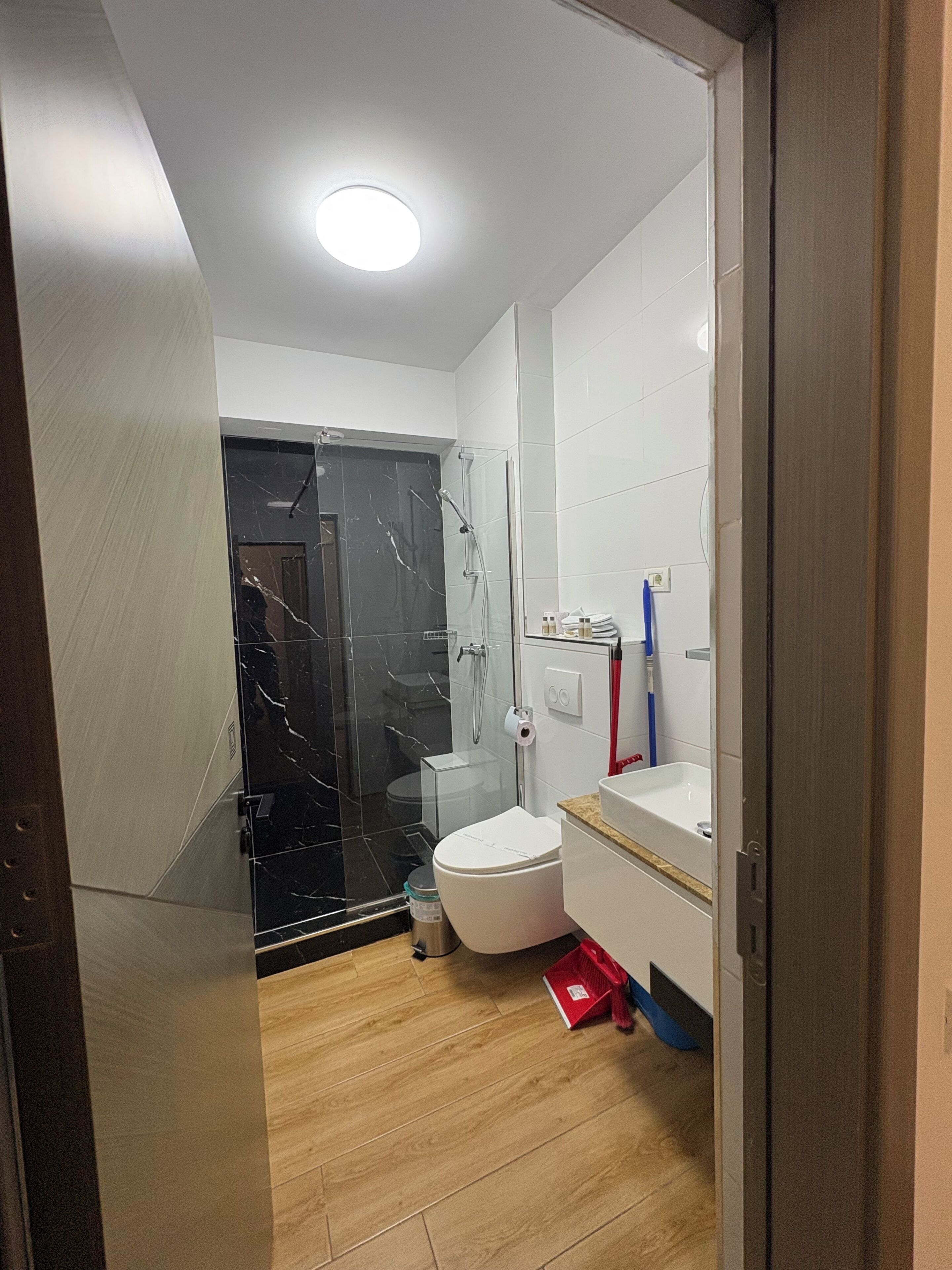 Un baño moderno con cabina de ducha de vidrio, inodoro blanco y lavabo con espejo.