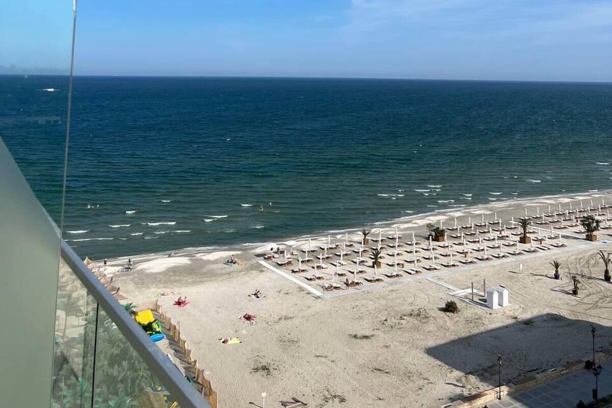 A beach with a clear sky, a sandy shore, and a view of the ocean.