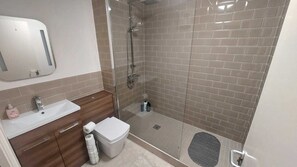 A bathroom with a shower, sink, toilet, and a mirror.