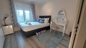 A bedroom with a bed, a desk with a mirror, a chair, and a nightstand. - Modern 2BD @ Trinity College & Temple Bar (Dublin)