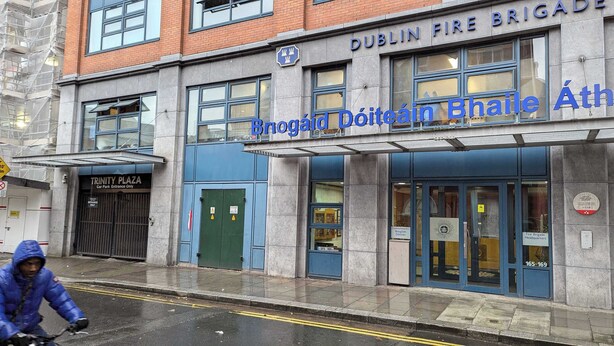 The Dublin Fire Brigade headquarters building with a clear entrance, a blue sign, and a visible fire hydrant outside.