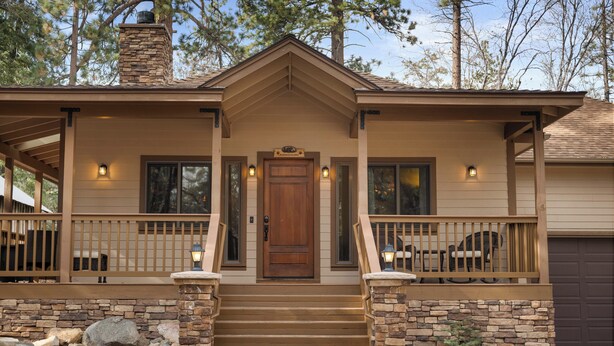 A two-story house with a front porch, stone steps, and a chimney.