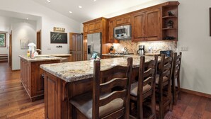 A spacious kitchen with wooden cabinets, granite countertops, and a central island with seating.