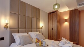 Une chambre d’hôtel avec un grand lit, deux tables de chevet, une armoire et un luminaire suspendu.