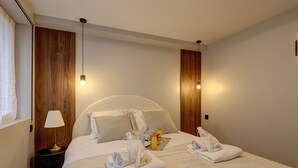 Een net opgemaakt bed met kussens, een bedlampje en een dienblad met ontbijtartikelen.